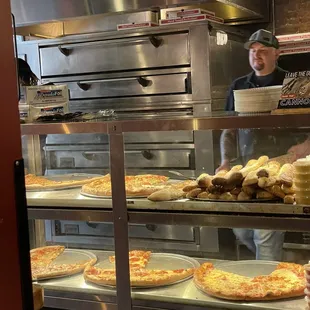 Pizza by the slice counter, bread &amp; warm sauces... pizza ovens in the background