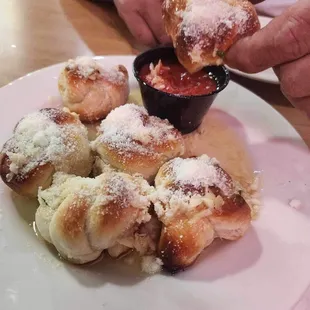 a person dipping a pastry into a bowl of sauce