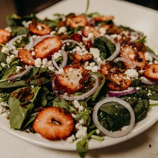 a salad with strawberries and onions