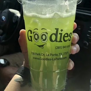 a person holding a cup of green juice