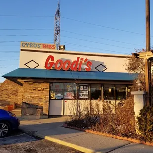 a blue car parked in front of a restaurant