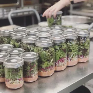 a table full of mason jars filled with salads