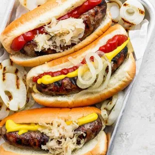 a tray of hot dogs with onions and ketchup