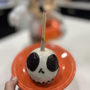 a person holding a plate with an apple with a candle sticking out of it