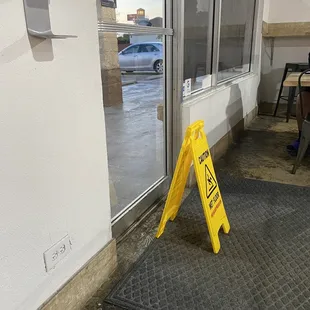 why? blocking the inside of the door, more chance of tripping over the sign than slipping on the not wet floor.