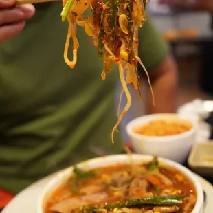 a person holding chopsticks over a bowl of food