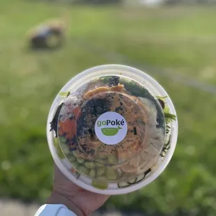 a person holding a plastic cup with a salad in it