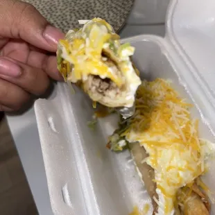 a person holding a sandwich in a styrofoam container