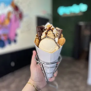 a hand holding a cone of ice cream