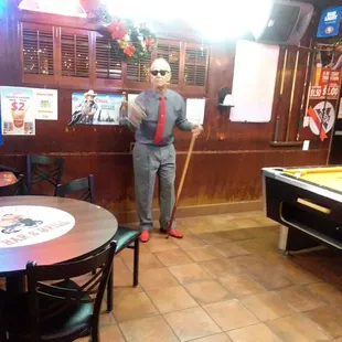 a man in a suit and tie standing in front of a pool table