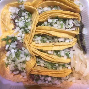 a variety of tacos in a styrofoam container