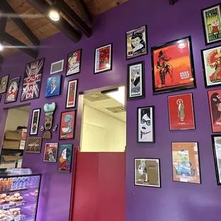 a purple wall with a variety of posters on it