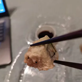 chopsticks holding up a piece of sushi