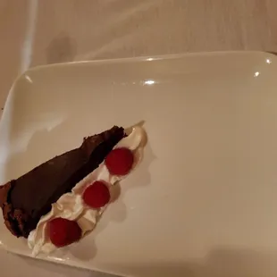 a piece of chocolate cake with whipped cream and raspberries