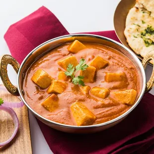 a bowl of curry and a plate of naan bread