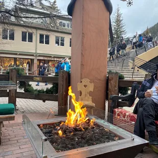 a man sitting on a bench next to a fire pit
