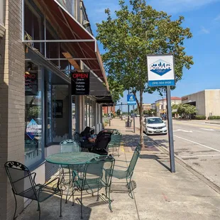 a sidewalk with tables and chairs