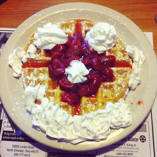 Belgium waffles with strawberries and whip cream.