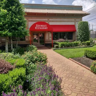 Outside entrance surrounded by blossoming flowers with butterflies