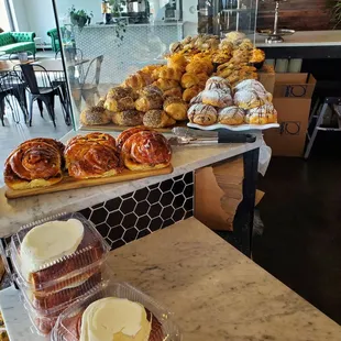 Huge iced cinnamon rolls in front, bakery selections