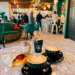 two cups of coffee and pastries on a marble table