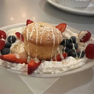 a dessert with whipped cream, strawberries, and blueberries