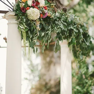 a wedding arch decorated with flowers and greenery