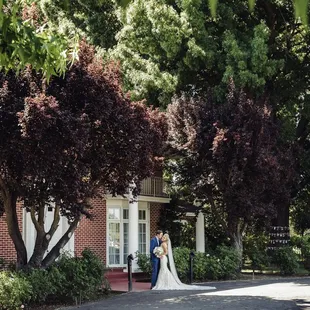 a bride and groom standing in front of a house