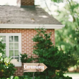 a wooden sign in front of a brick house
