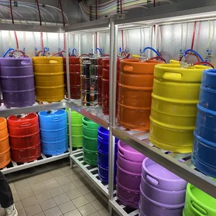 a man standing in a kitchen with a rack of kegs