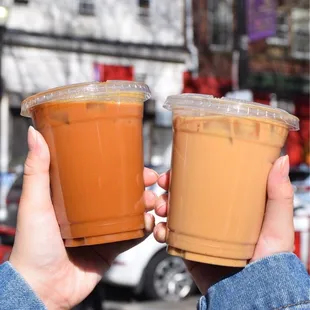 two people holding cups of iced coffee