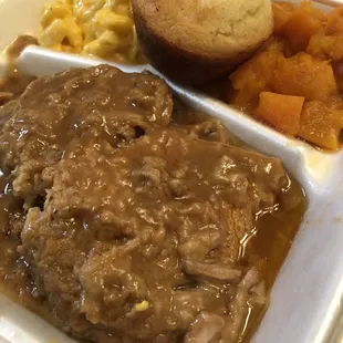 2 thick smothered pork chops with sweet potatoes, macaroni and cheese and cornbread