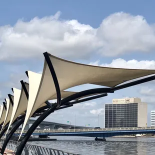 a row of shade sails on a bridge over a river