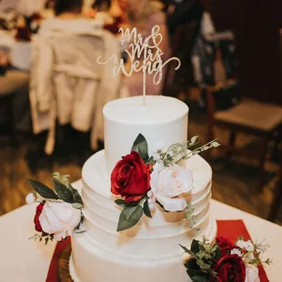 a white wedding cake with red flowers