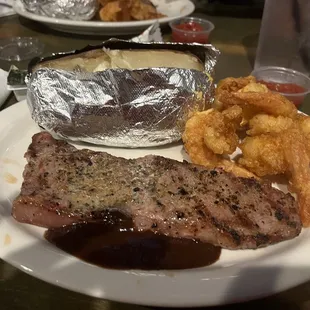 a plate of steak, potatoes, and onion rings