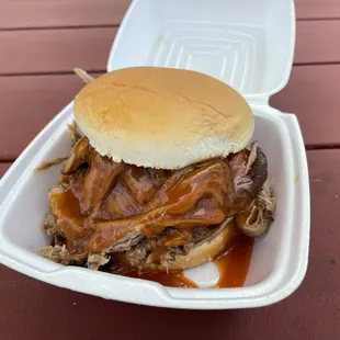 a pulled pork sandwich in a styrofoam container
