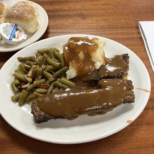 a plate of meat, gravy and green beans