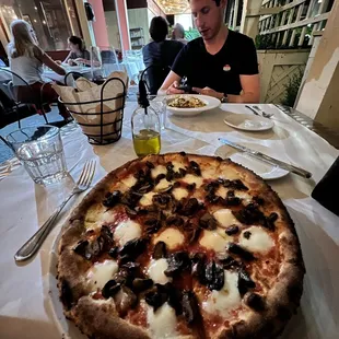 a man sitting at a table with a pizza