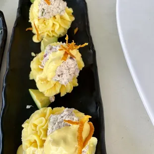 a black rectangular plate with three appetizers on it