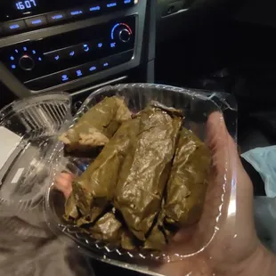 a person holding a tray of stuffed grape leaves