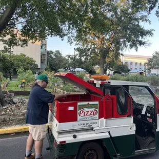 a man putting pizza in the back of a truck