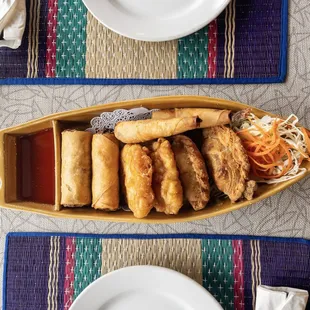 NEW ITEM: Boat Deluxe - Two of each item: Eggrolls, Corn cake, Shrimp blanket, and Curry Puff. Paired with a sweet Chili and cucumber salad,