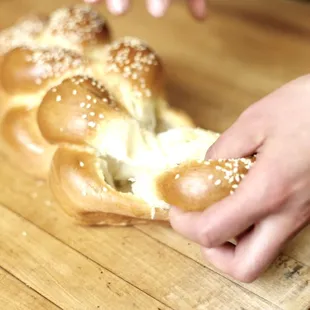 a person's hand reaching for a piece of bread