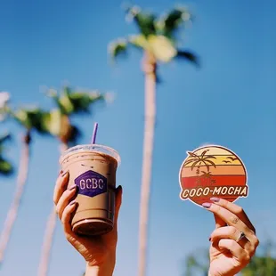 a person holding a drink and a sticker