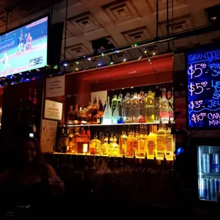 a bar with neon signs and liquor bottles