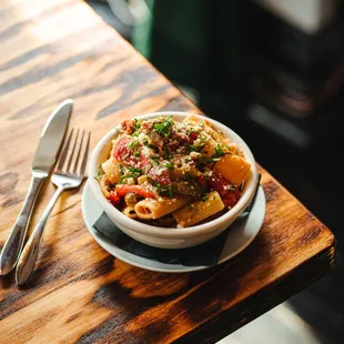 a bowl of pasta and a fork on a wooden table