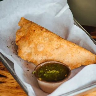 a deep fried calzone with a side of pesto sauce