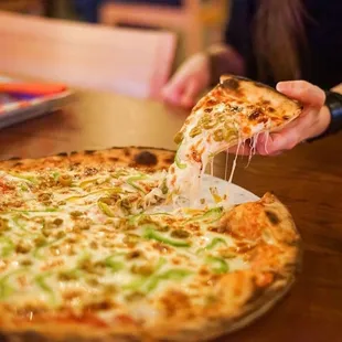 a person taking a slice of pizza