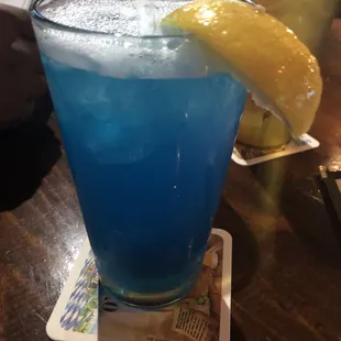 a blue drink with a lemon wedge