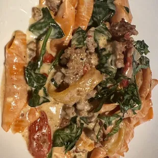 a plate of pasta with sausage and spinach